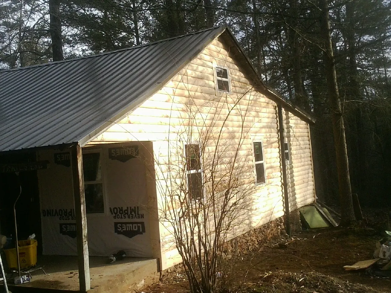 Log siding gable end under a dark metal roof edge in Stonewall