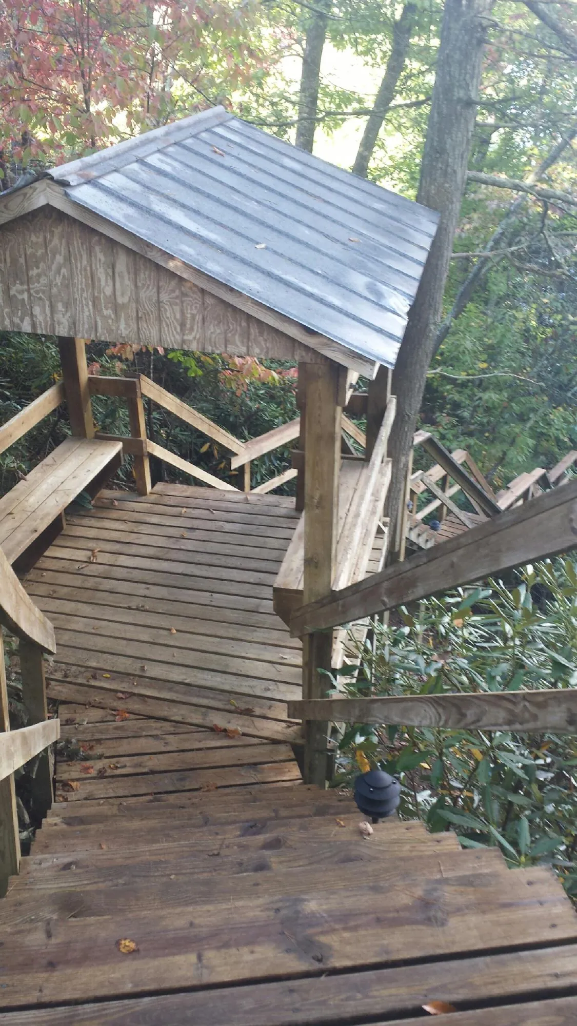 Metal roofed shelter over wooden steps on a wooded walkway — Skylight Repair & Installation work by our crew in Stonewall